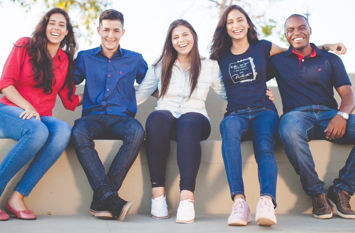 Five smiling students sitting in a row